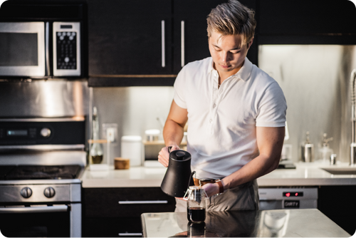 A person brewing pour over coffee at home using single serve drip bag from Hooked Coffee